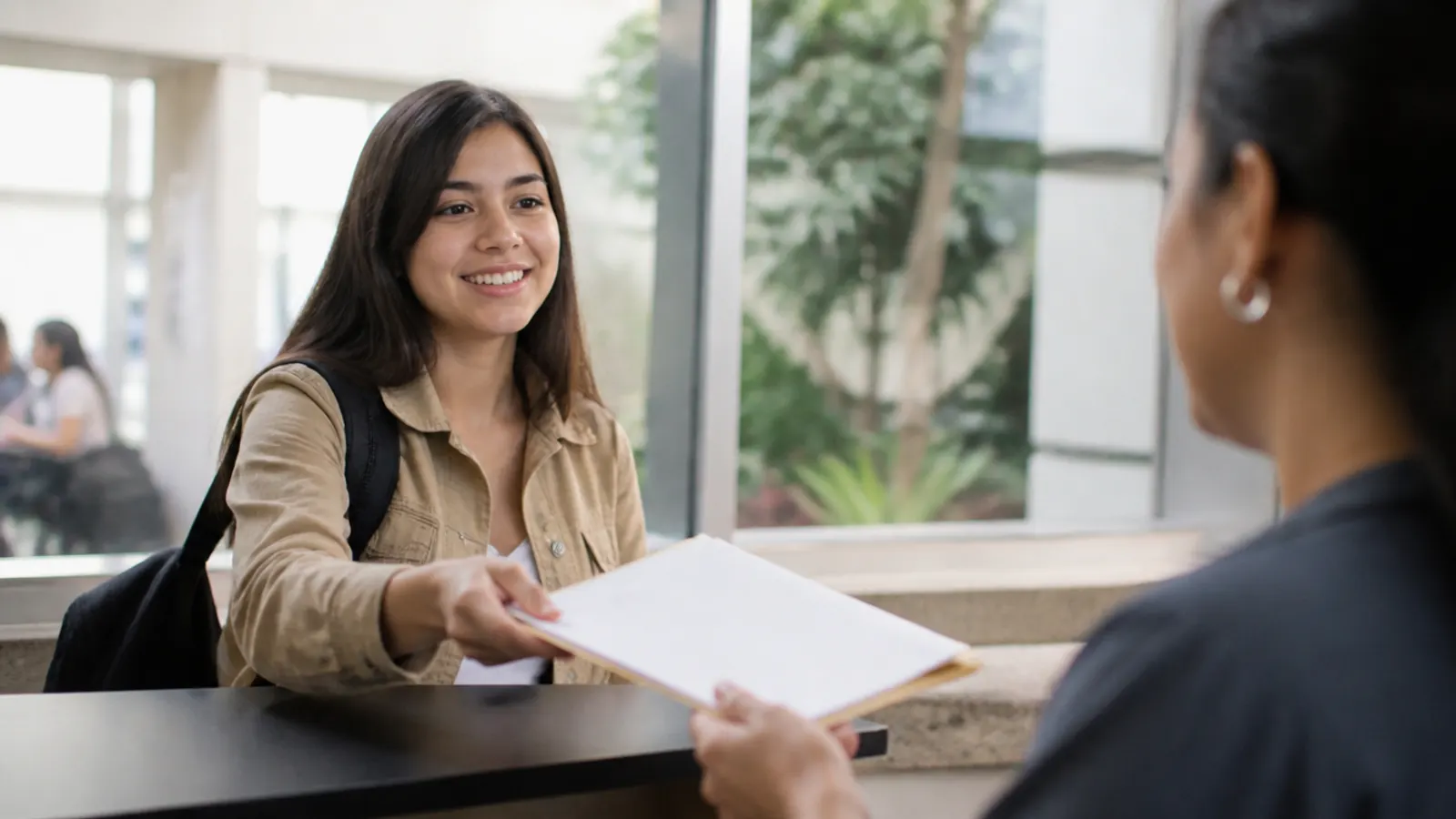 Estudiante entregando su solicitud de beca en la ventanilla de la universidad